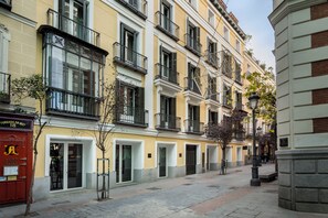 Una hilera de edificios amarillos con balcones, un buzón rojo y una farola.