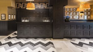 Een moderne barruimte met geometrische wandpatronen, hanglampen en een vloer met dessin.