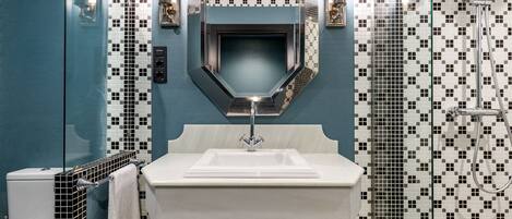 A bathroom with a white sink, a mirror, and a shower.