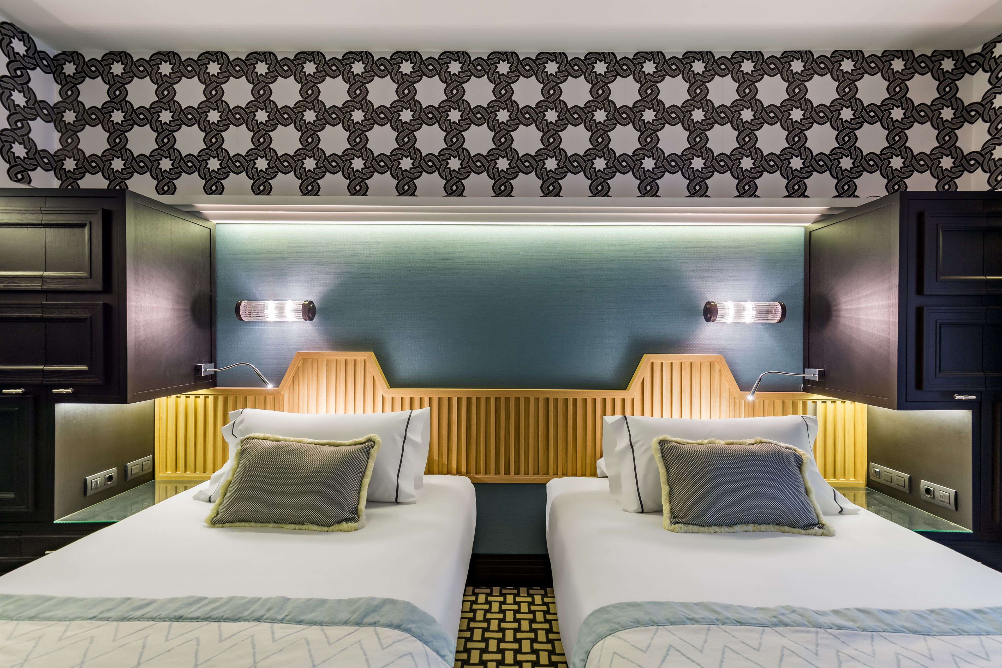 Une chambre d’hôtel avec deux lits, un plafond décoré et un design moderne.