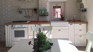 Una cocina con paredes de ladrillo blanco, una estufa blanca y un letrero que dice 'Cuisine' sobre la ventana.