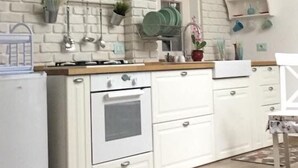 Una cocina con muebles blancos, pared de ladrillo y un letrero que dice 'Cuisine'.