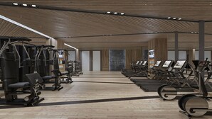 Un gimnasio moderno con diversos equipos de ejercicio, piso de madera y techo alto.