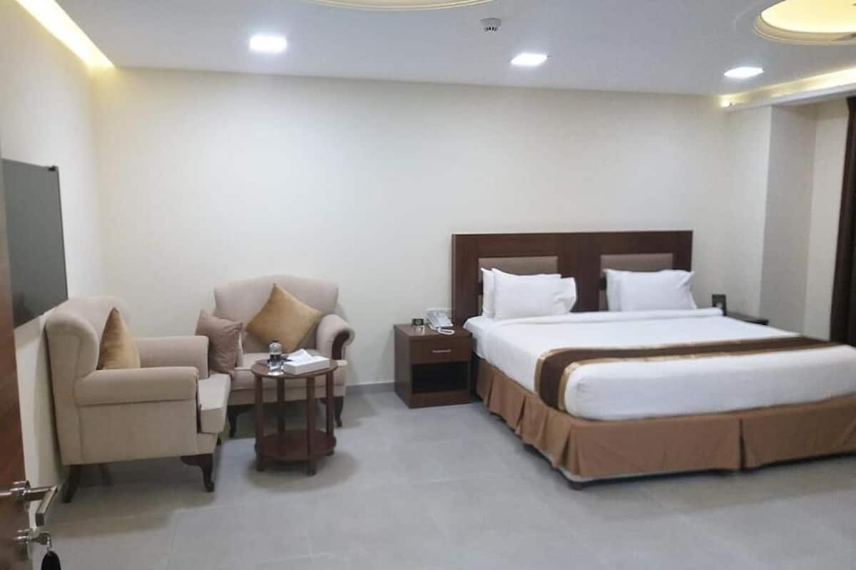 Una habitación de hotel con una cama, un sofá, una mesita y una mesita de noche.