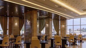 Un comedor moderno con mesas y sillas, ventanas amplias y vistas al exterior.
