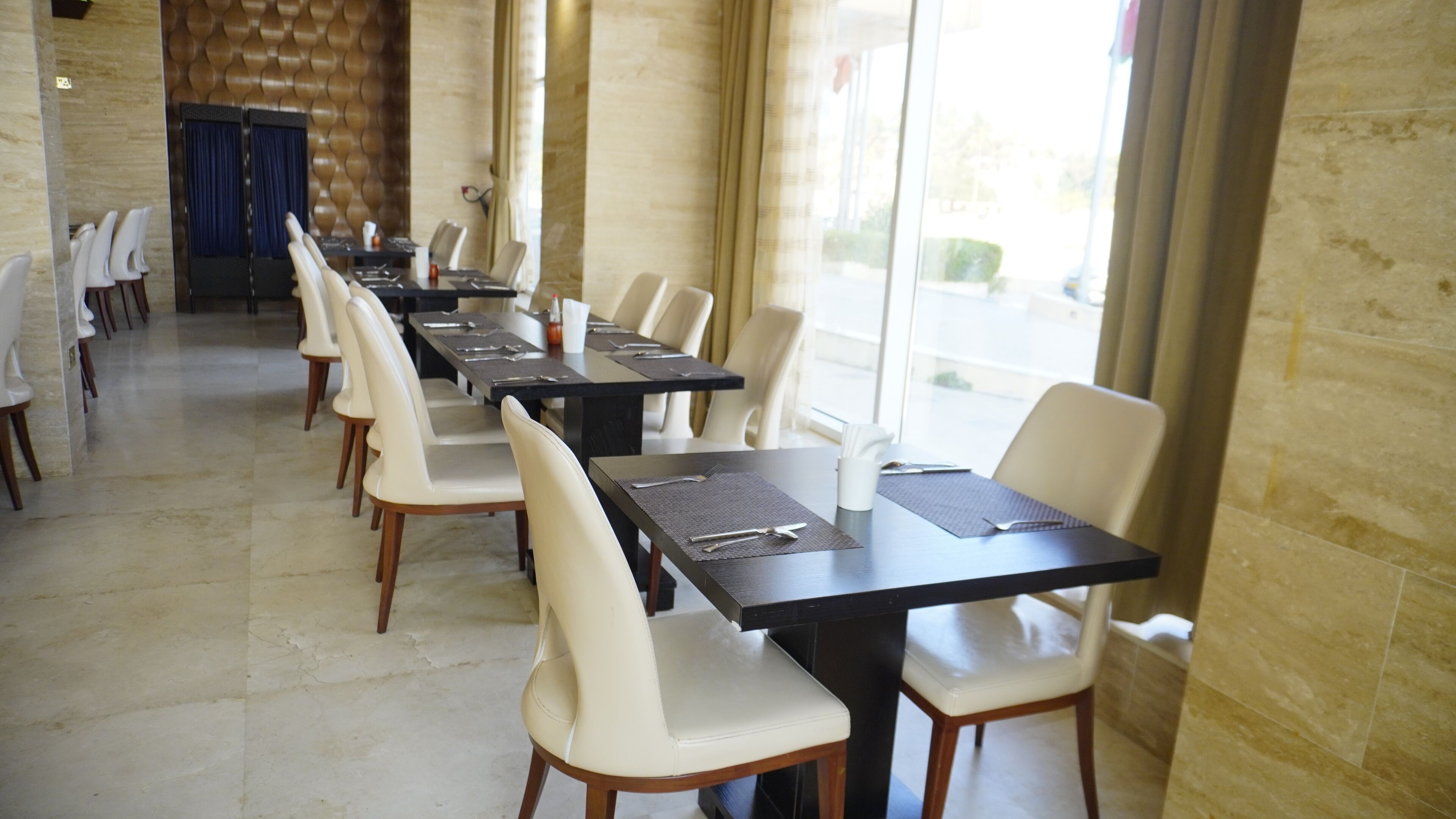 A long dining table with chairs, a stone wall, and a view of the street.