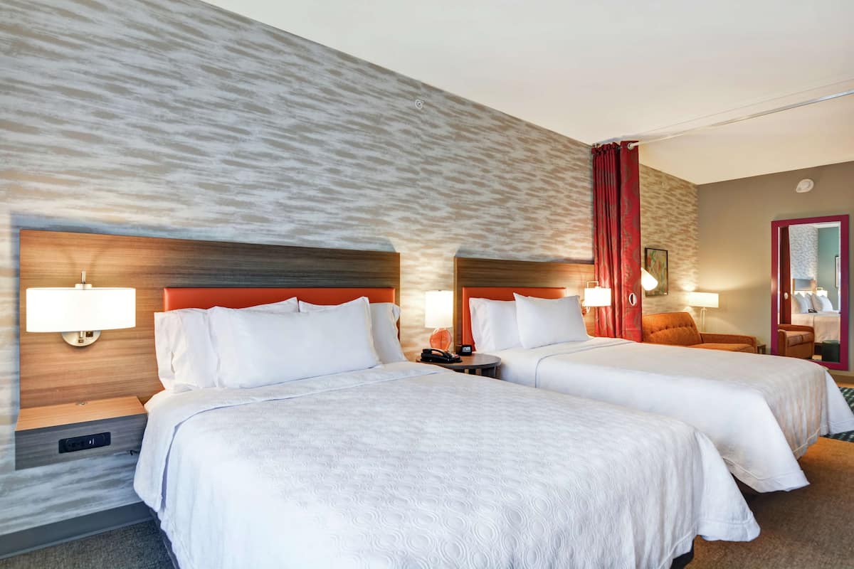 Ein Hotelzimmer mit zwei Betten, Holzkopfteilen und einer strukturierten Wand.