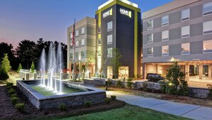 A modern hotel with a central fountain, multiple stories, and a well-lit entrance.