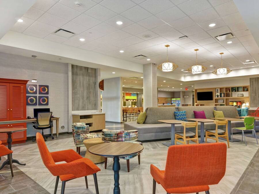 A modern hotel lobby with seating areas, a reception desk, and a dining area.