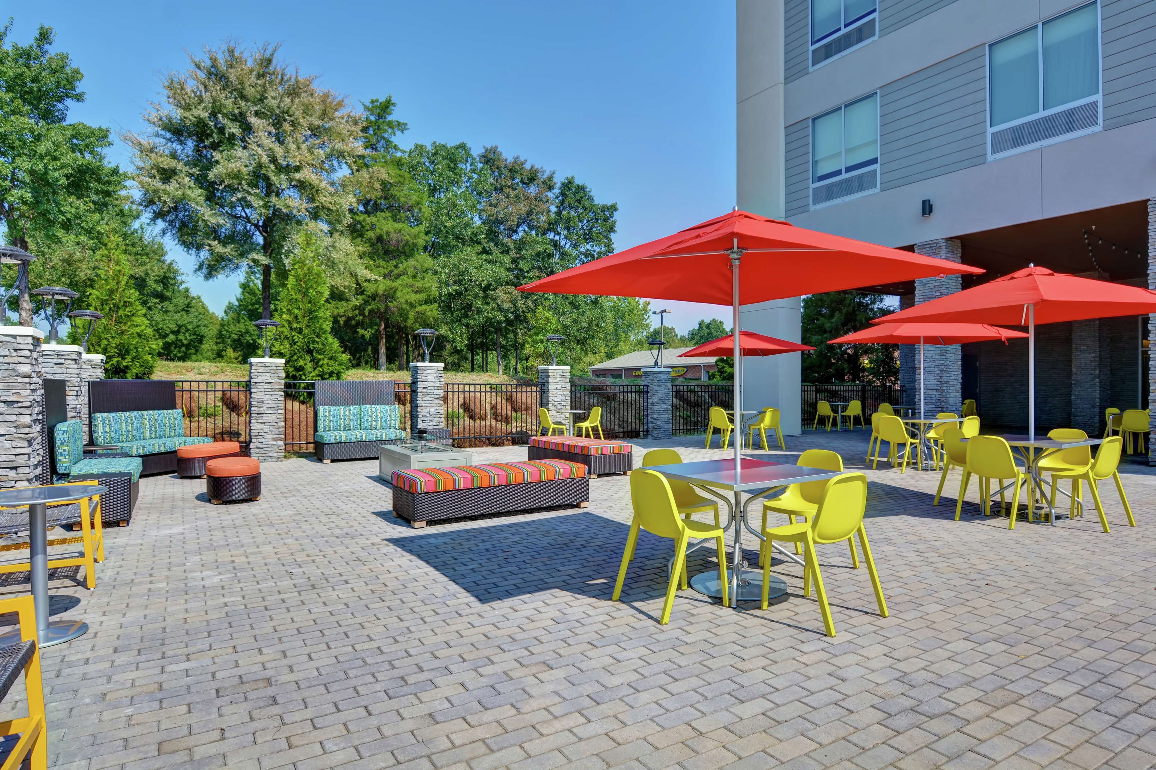 Un espace extérieur aménagé en terrasse, avec des sièges, des tables et des parasols.