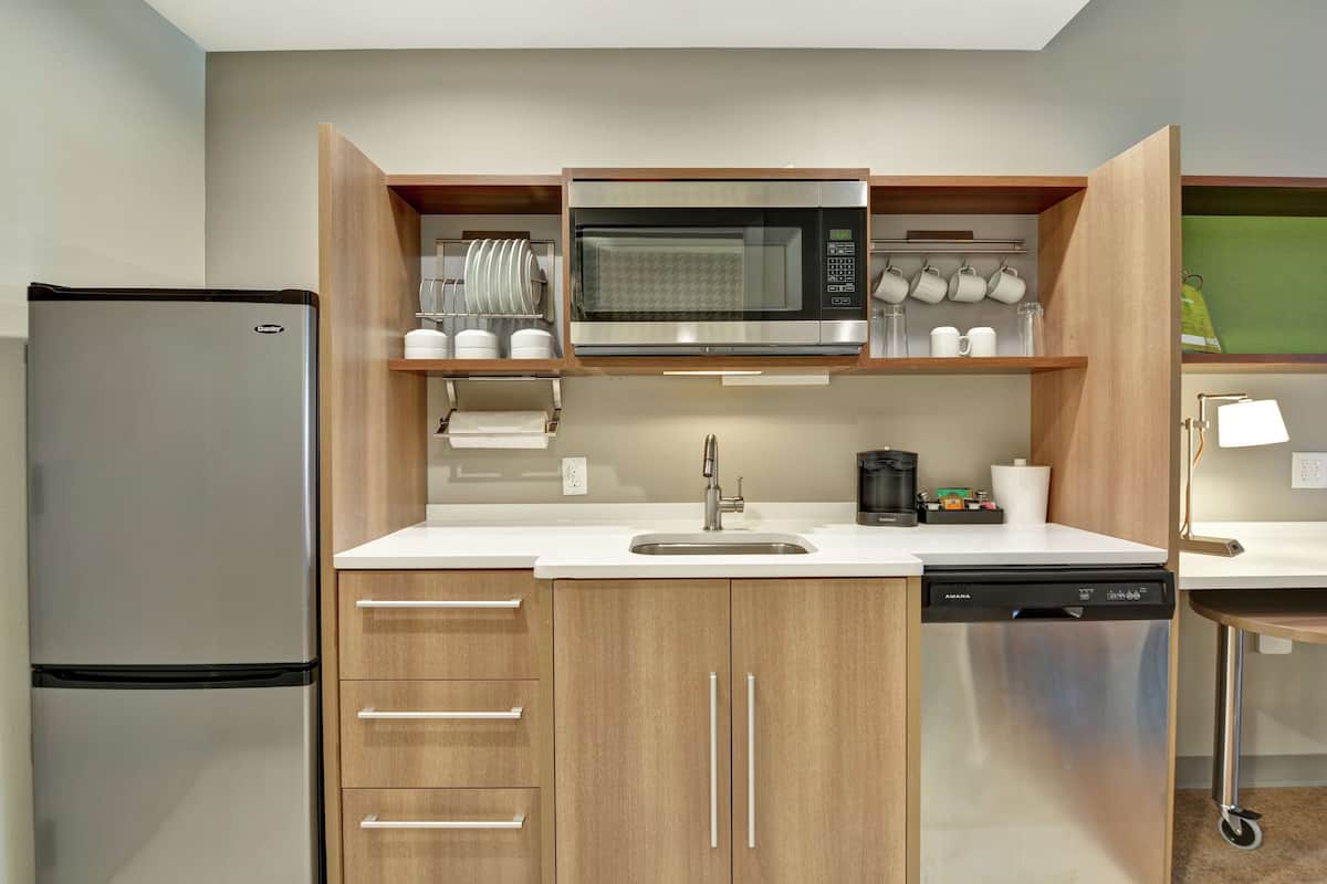 Eine kompakte Küche mit Edelstahl-Kühlschrank, Mikrowelle und Geschirrspüler.