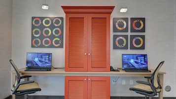 Ein Arbeitsplatz mit zwei Laptops, zwei Stühlen und einem großen, roten Schrank mit zwei Türen.
