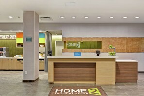 A hotel reception area with a check-in counter, a digital display, and a reception desk.