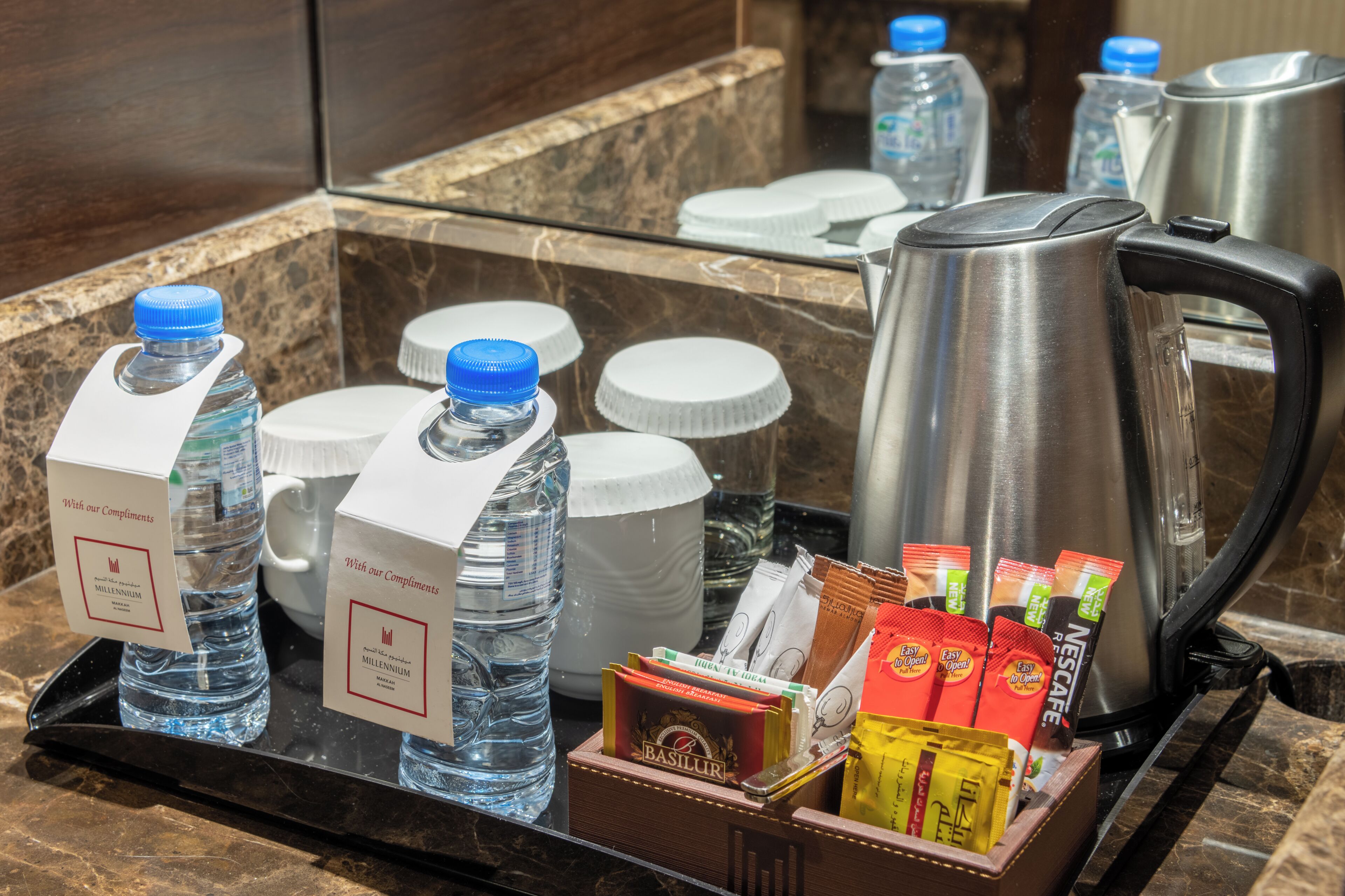 A hotel room's minibar area with water bottles, a coffee maker, and various food items.