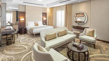 Ein Hotelzimmer mit einem großen Bett, zwei Sofas, einem Couchtisch und einem Schreibtisch mit Stuhl.