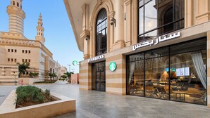 Una Starbucks dentro de un edificio con un gran ventanal y un letrero en árabe.