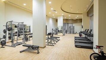Un gimnasio con máquinas de cardio, equipo de levantamiento de pesas y bancos.