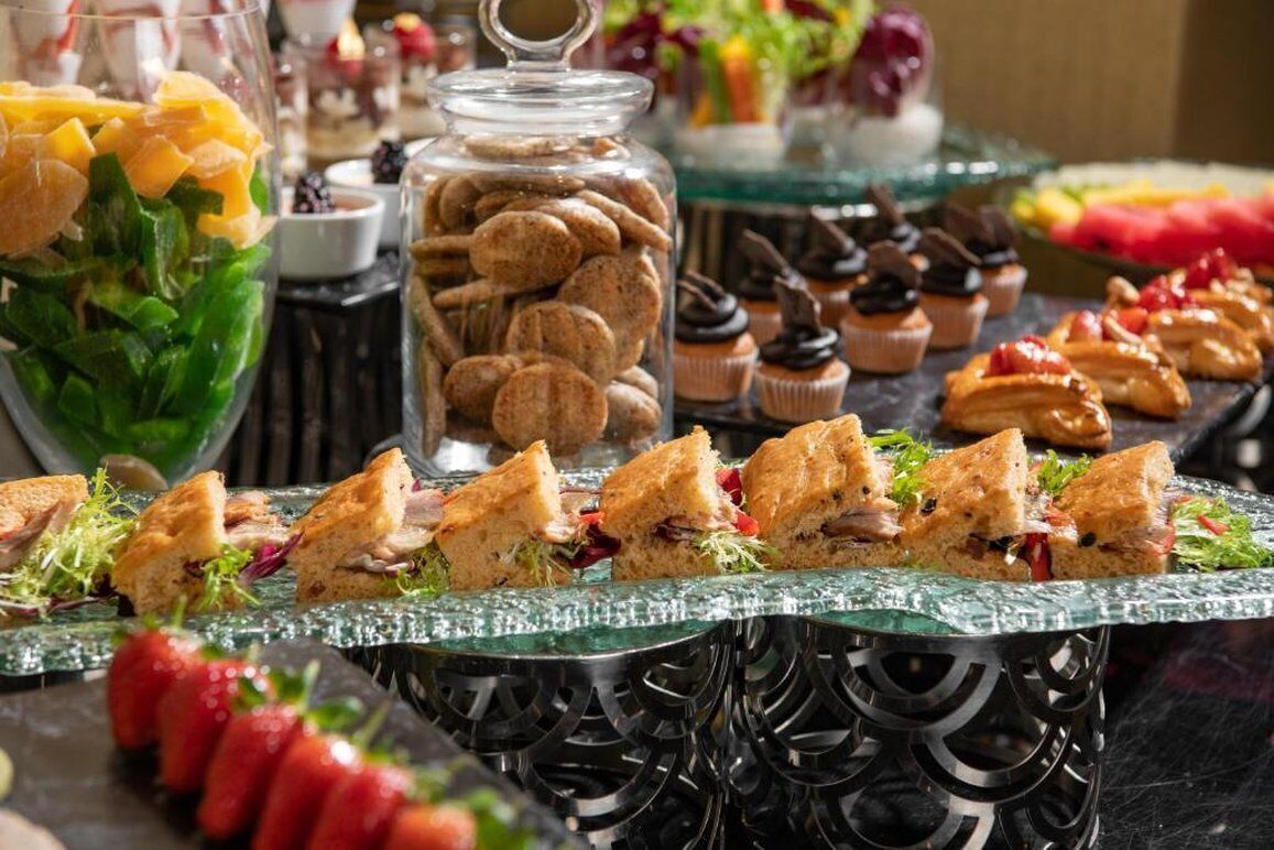 Ein reichhaltiges Buffet mit verschiedenen Speisen, darunter Sandwiches, Kekse und Desserts.