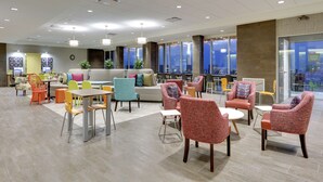 A spacious lobby with modern furniture, large windows offering city views, and a variety of seating options. - Home2 Suites BY Hilton Hagerstown (Hagerstown)