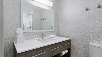 Une salle de bain moderne avec un lavabo blanc, un grand miroir et des toilettes.