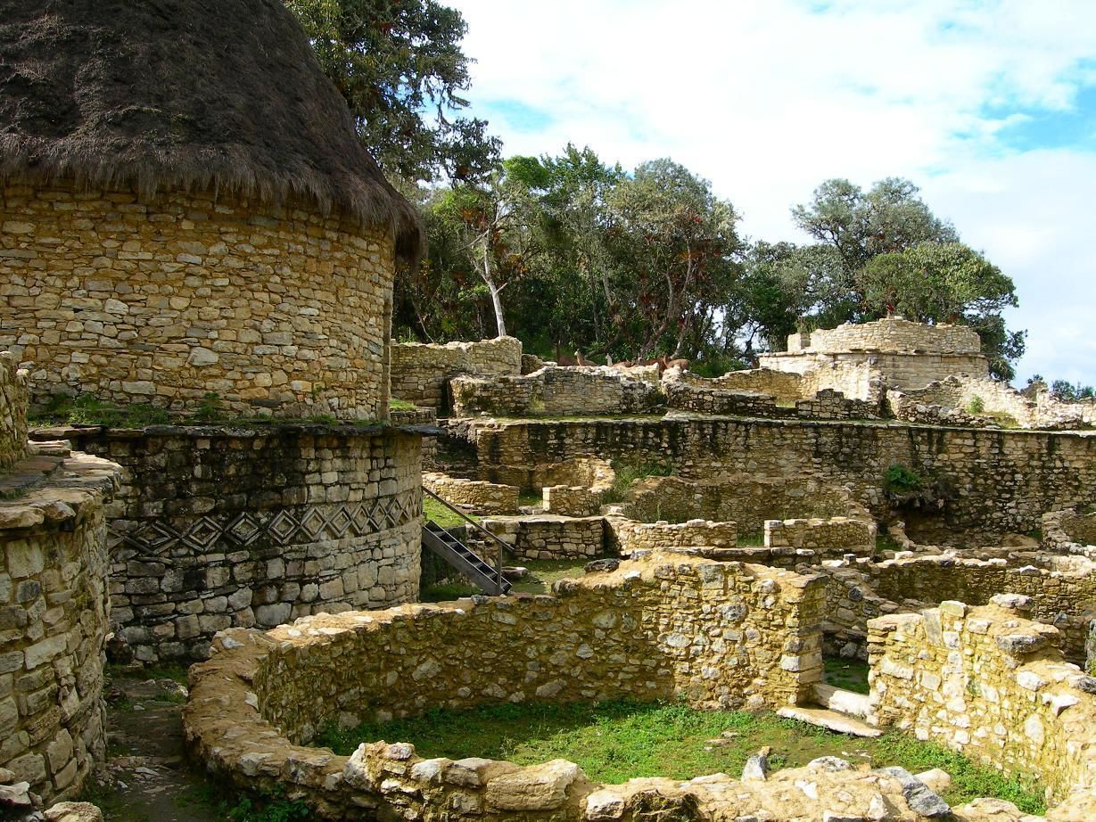 Ancient stone ruins with circular structures and a thatched-roof building.