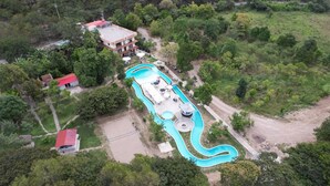 An aerial view of a resort with a swimming pool, a small building with a red roof, and surrounding greenery. - Zoila's Suite Escape (Tingo)