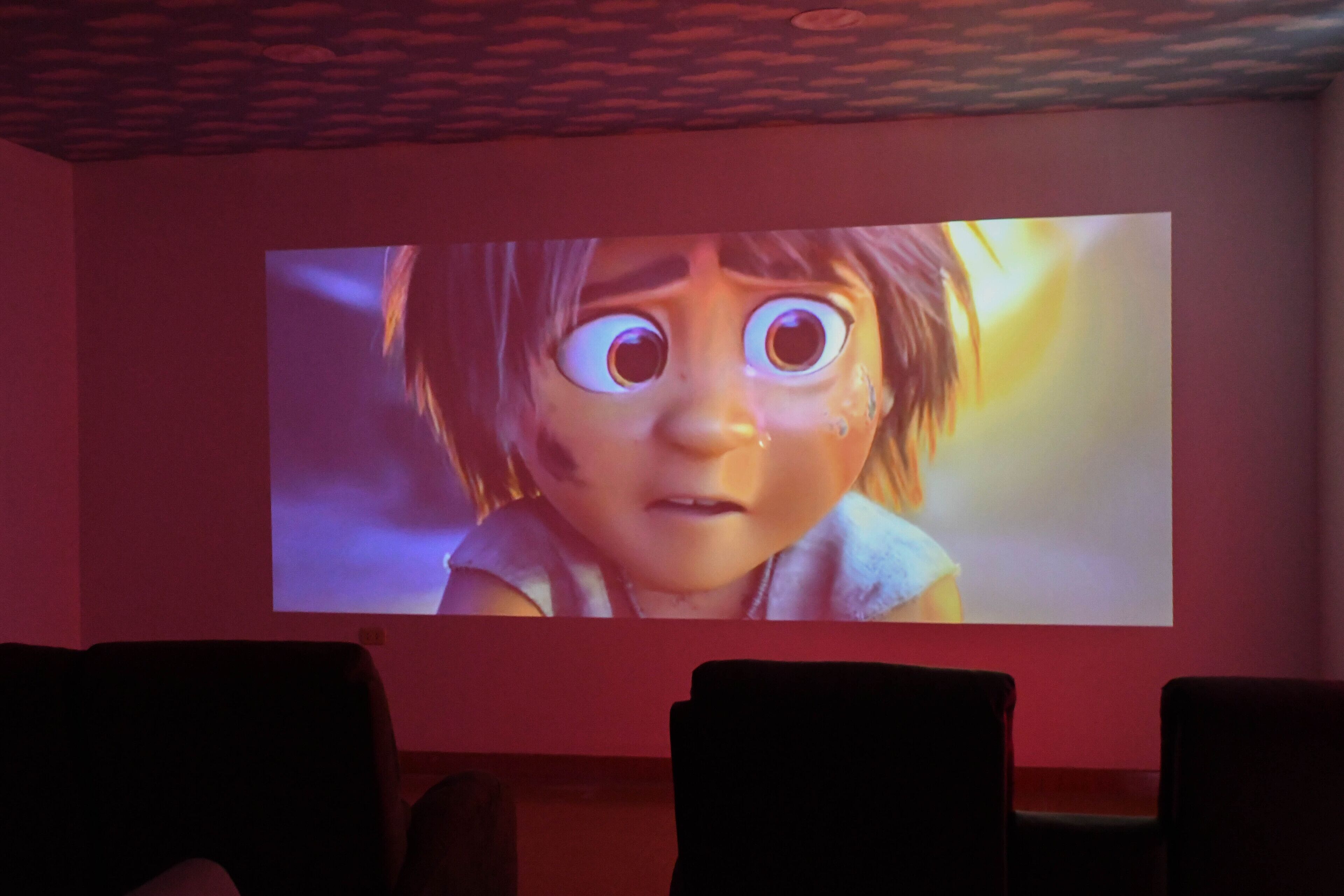 A movie screen in a theater with a dark interior and rows of seats.