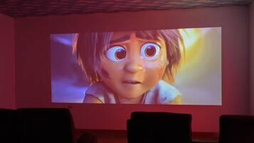 Una pantalla de cine en un cine con un interior oscuro y filas de asientos.