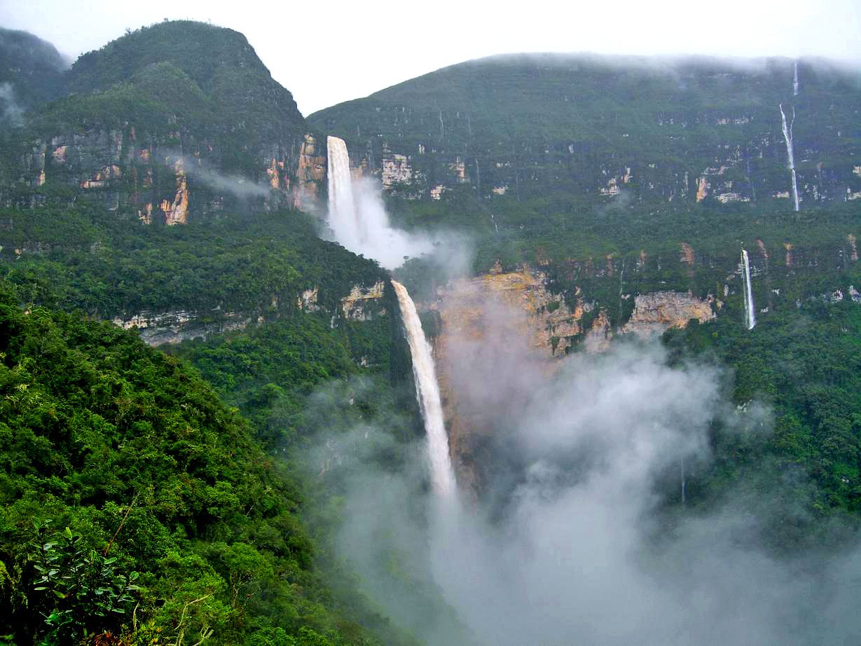 A waterfall cascading down a lush green valley with steep cliffs and dense vegetation.