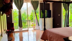 A bedroom with a four-poster bed, a ceiling fan, and a balcony with a view of greenery. - Zoila's Suite Escape (Tingo)