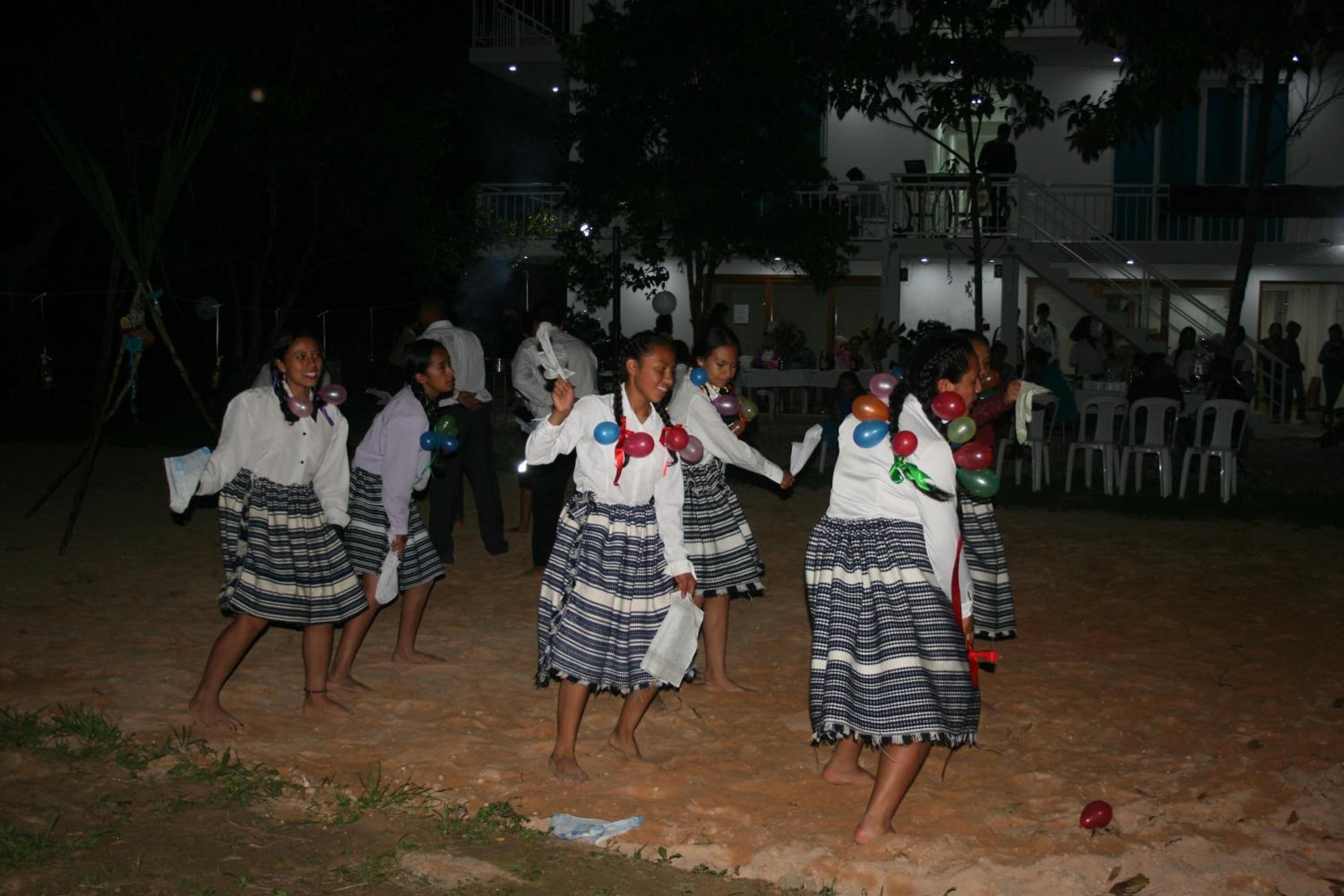 A group of people dancing in an outdoor setting with a building in the background.