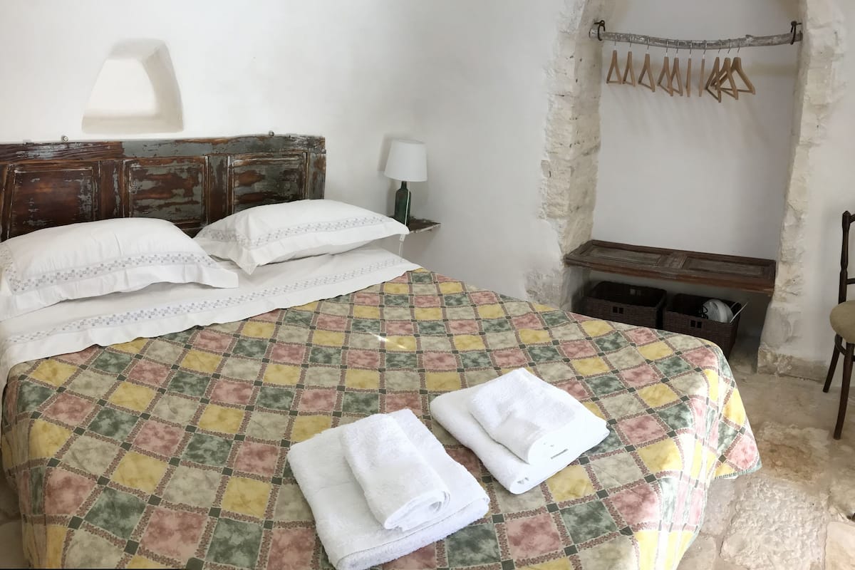 A bed with a quilt, pillows, and folded towels.