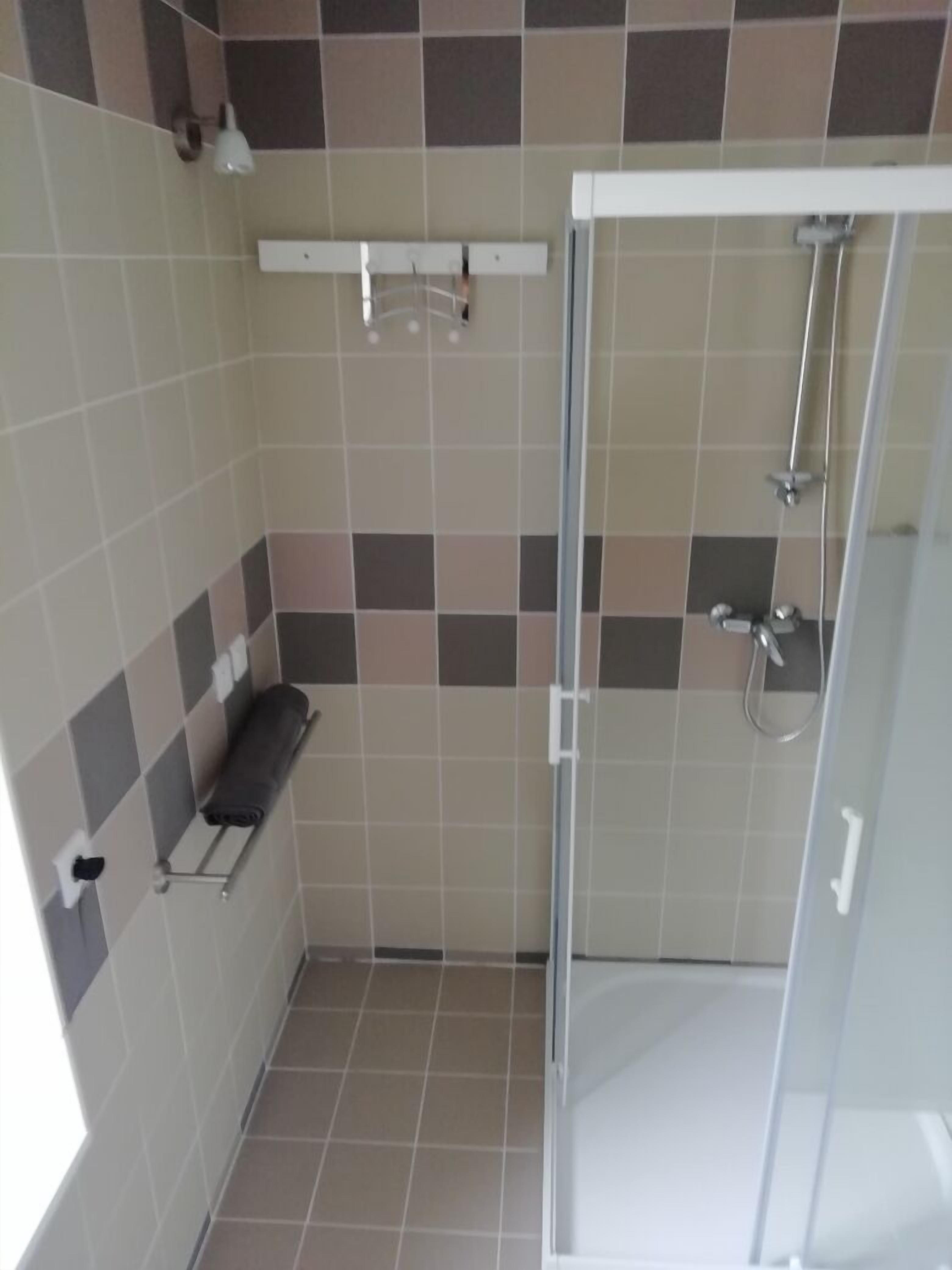 Ein kleines Badezimmer mit Dusche, Handtuchhalter und Toilette.