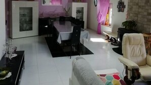 A spacious living area with a dining table, a sofa, and a kitchen in the background.