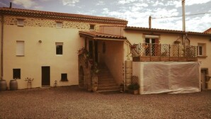 A building with a tiled roof, a covered entrance, and a gravel courtyard.