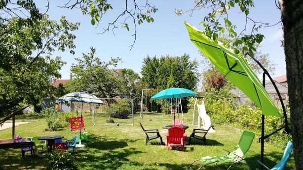 A backyard with a swing set, a table with chairs, and a small garden area.