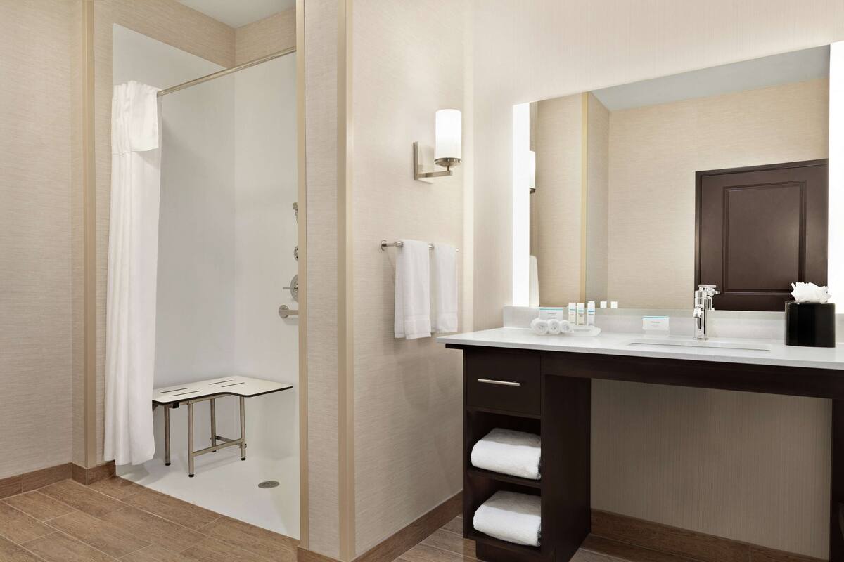 A modern bathroom with a shower, a sink with a mirror, and a towel rack.