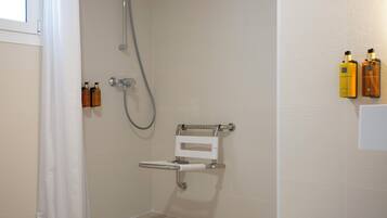 A shower area with a grab bar, a handheld showerhead, and toiletries on the wall.