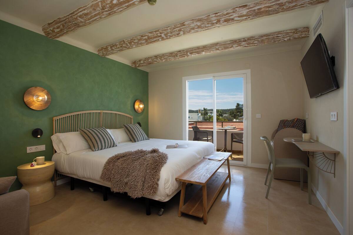 A bedroom with a bed, bedside table, chair, and a view of the outdoors through a sliding door.