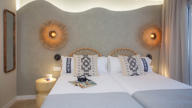 Ein Doppelbett mit zwei Kissen, ein Nachttisch und Wandleuchten.