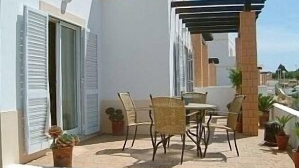 An outdoor patio with a table and chairs, potted plants, and a pergola.