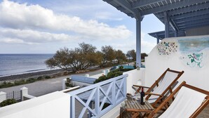 Un balcone con vista sul mare, sedie a sdraio in legno e un muro decorativo.