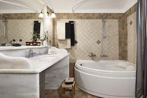 A bathroom with a large bathtub, a double sink, a mirror, and a shower.
