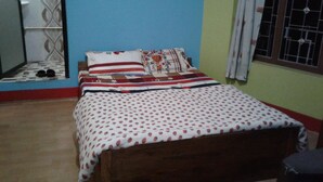 Un dormitorio con una cama de madera, una colcha estampada y una almohada floral.