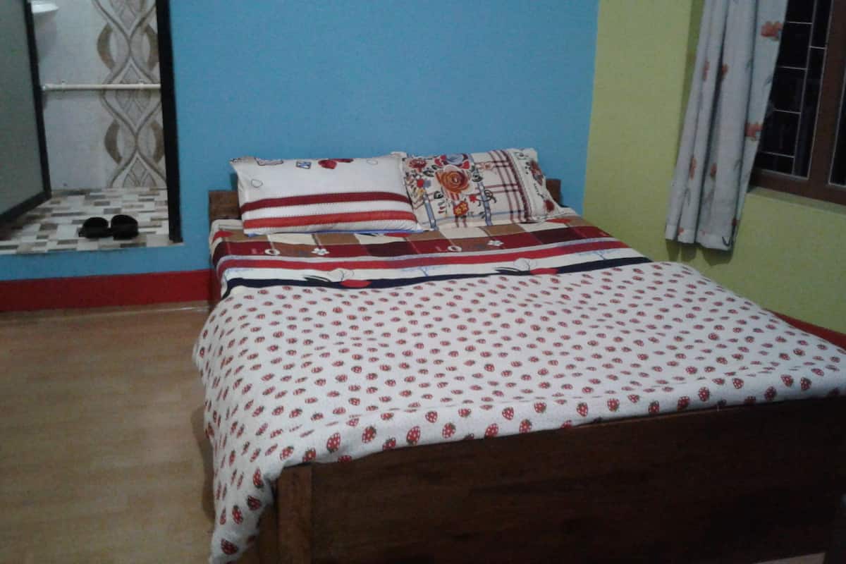 A bedroom with a wooden bed, a patterned bedspread, and a floral pillow.