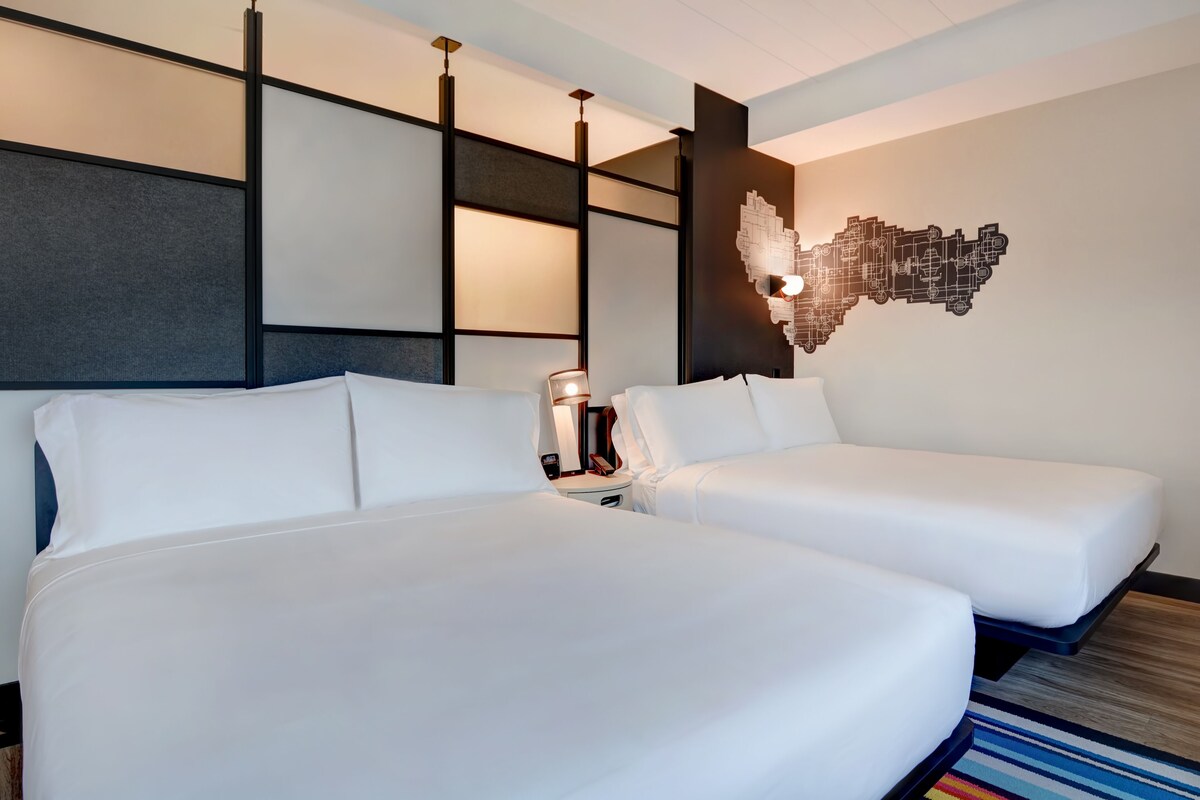 A hotel room with two beds, a modern wall design, and a unique wall art piece.