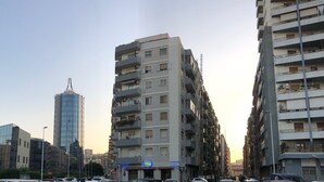 A multi-story building with balconies, a visible restaurant sign, and a clear sky. - Arya Cagliari (Cagliari)