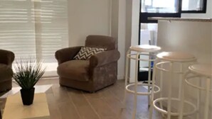 Un salon moderne avec un canapé marron, une petite table blanche et une plante en pot.