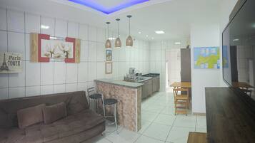 A modern kitchen with a central island, bar stools, and a dining table.