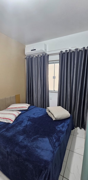 Une chambre à coucher avec un lit, des rideaux, une fenêtre et un radiateur.